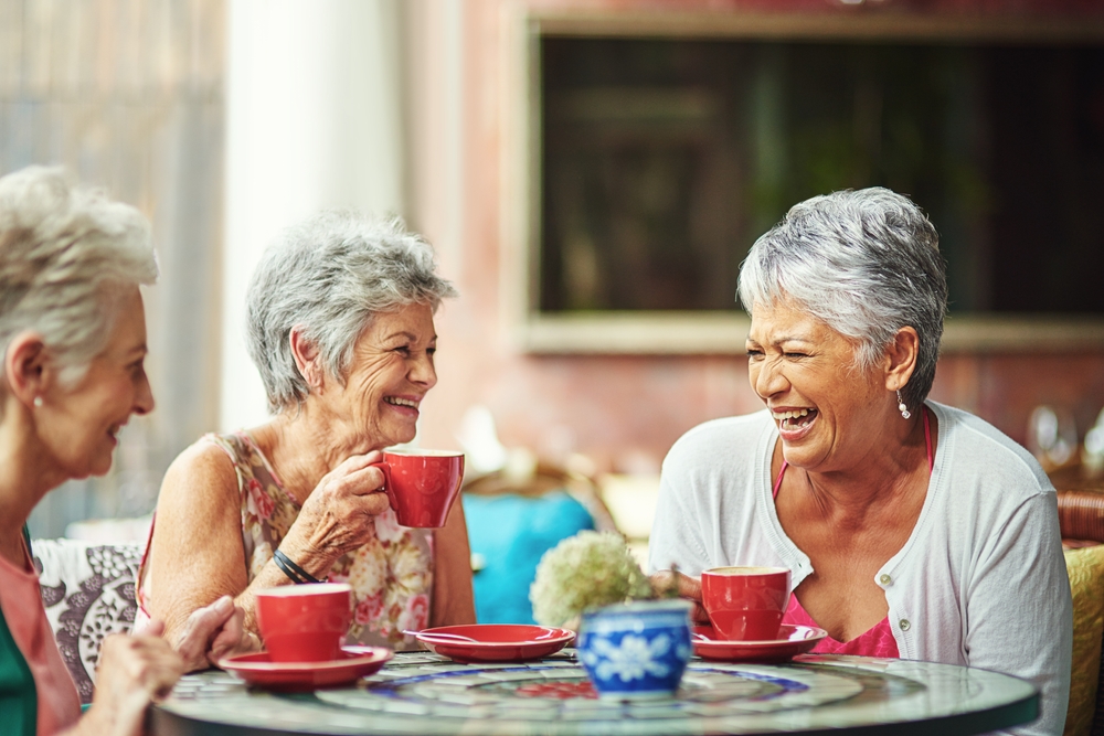 A group of senior women chat over coffee.
