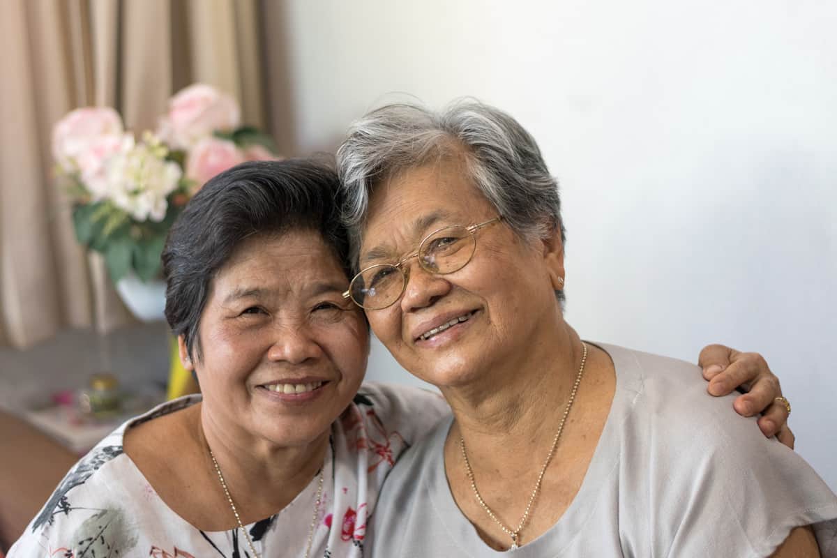 a senior woman and her daughter smile and sit together