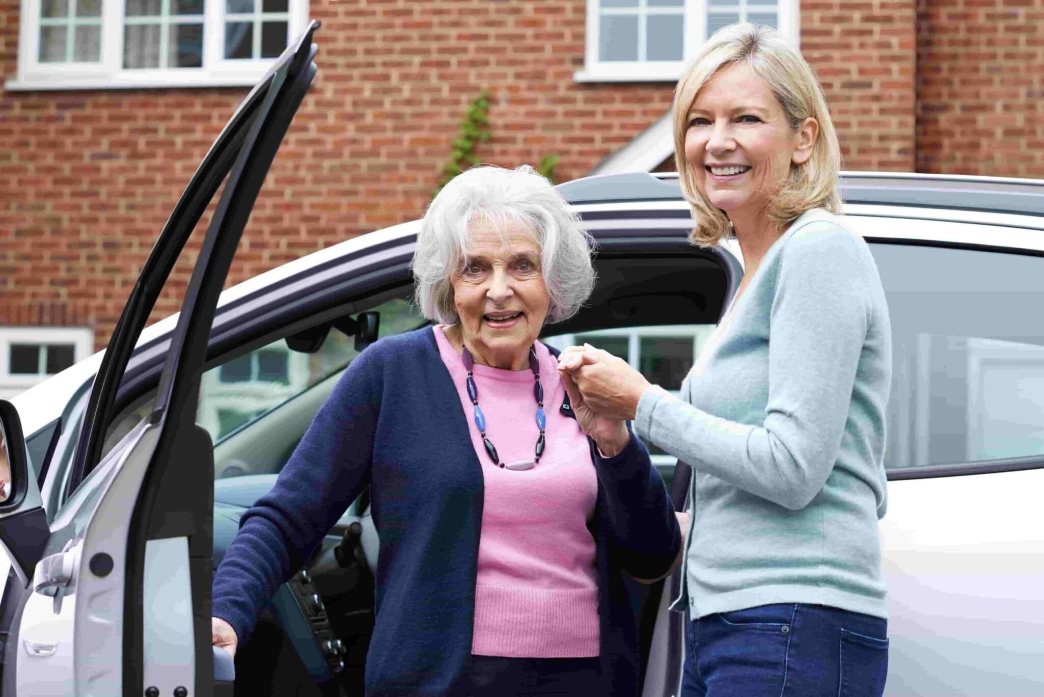 woman helping elderly woman out of car