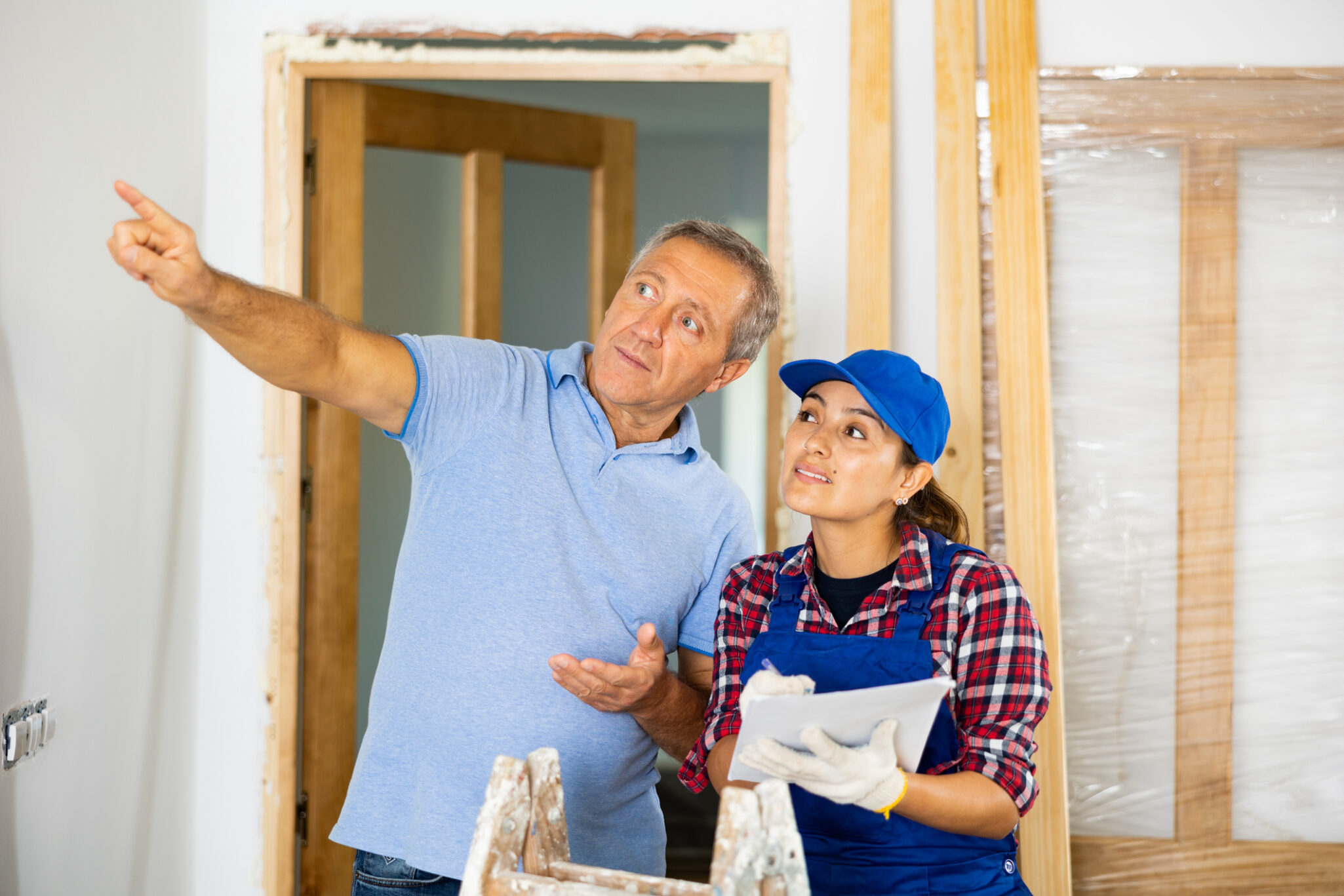 A man outstretches his arm, pointing into the distance while talking with a home construction team member who is helping build or remodel the home