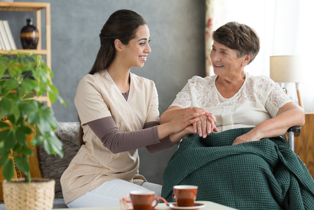 Senior woman sitting with caregiver in rehab